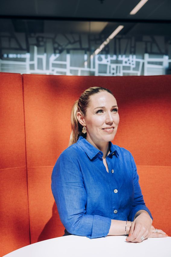 Maija Jokela istumassa neuvottelutilassa oranssilla sohvalla.