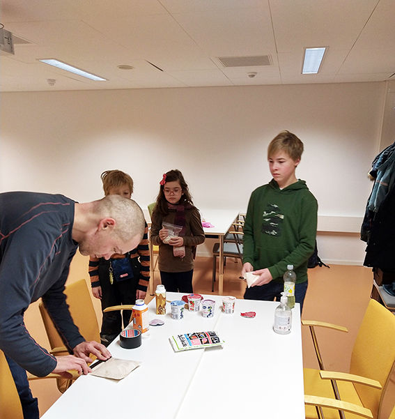 Lecturer Jami Kinnunen with three children sealing a bag at a table