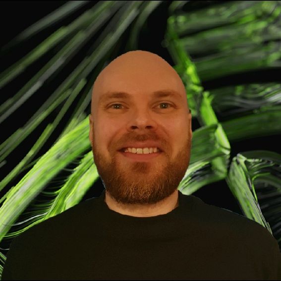 A man smiling at the camera with leaves in the background
