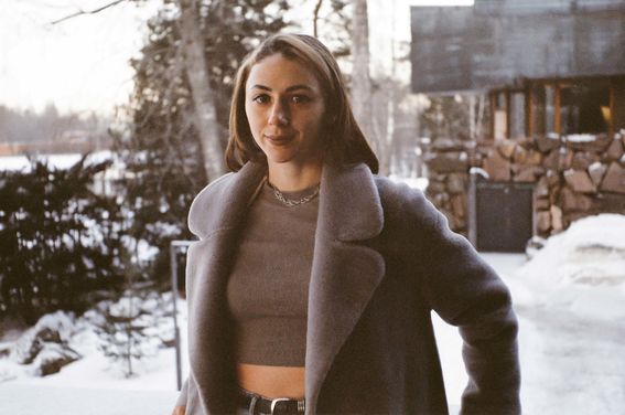 A woman stands in front of a snowy background at the Dipoli building in Otaniemi, Finland. 