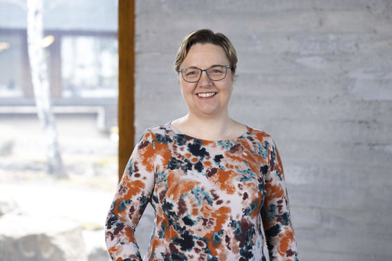 Hymyilevä Raili Pönni seisoo neuvotteluhuoneessa, taustalla näkyy ikkunasta Dipolin piha-aluetta.