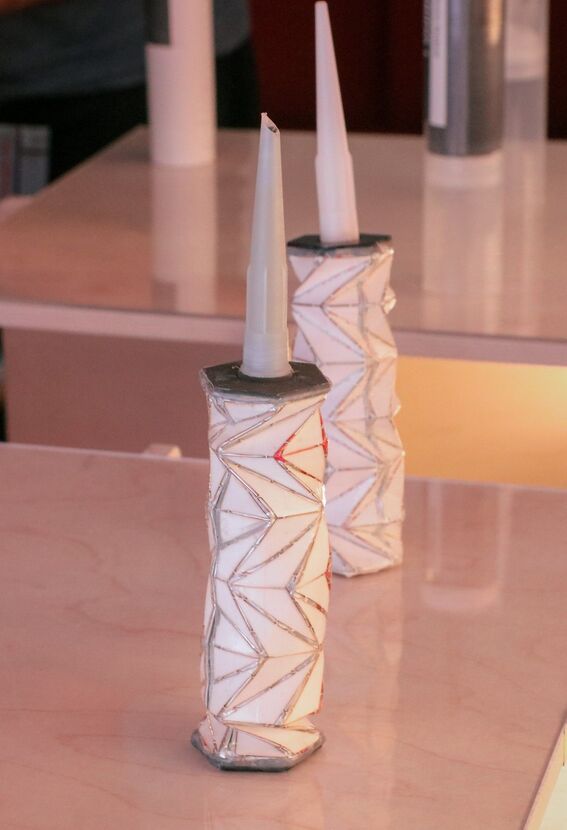 Two white containers with geometric patterns on a table.