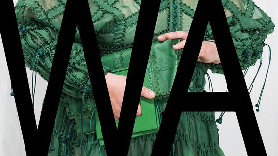 Person in a detailed green dress holding a green book, partially obscured by large black letters 'WA'.