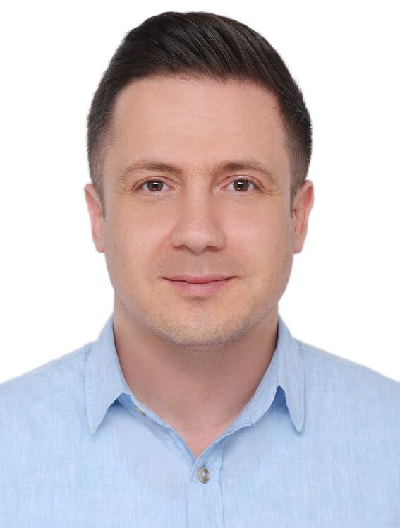 Muotokuva henkilöstä, jonka kasvot on blurattu, tumma tukka ja vaaleansininen kauluspaita valkoista taustaa vasten