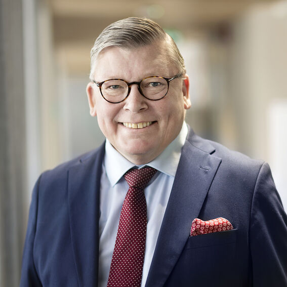 Liikemies tummansinisessä puvussa, punainen pilkullinen kravatti ja taskuliina