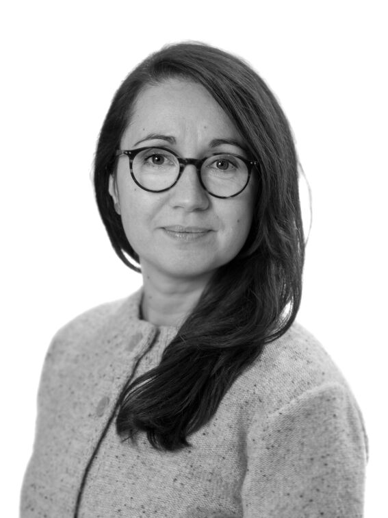Black-and-white portrait of a woman in a light textured jacket, with long dark hair, face blurred