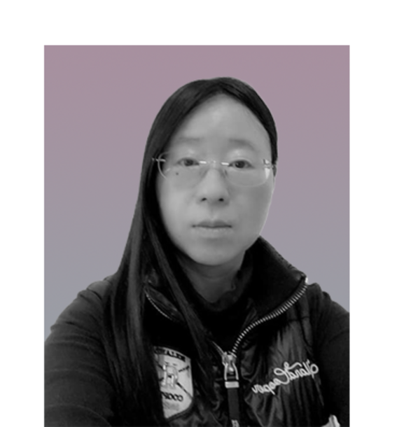 Person in dark jacket with long hair, face blurred, posing against a soft purple-grey background