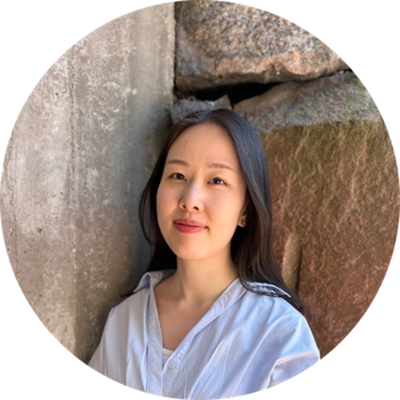 Person with long dark hair in a light shirt, standing by rough stone and concrete walls