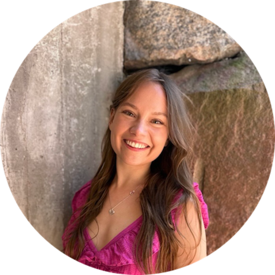 Person with long brown hair in a pink dress, standing by rough stone and concrete walls, face blurred