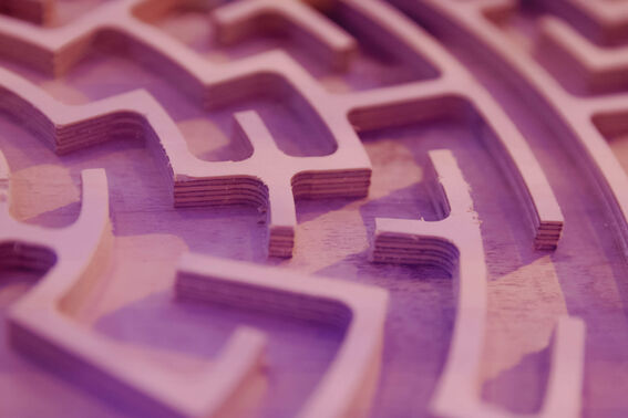 Lähikuva monikerroksisesta puumaisesta labyrinttikuviosta vaaleanpunaisessa ja violetissa valossa