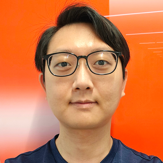 Person in blue shirt with blurred face, standing against bright orange wall with light reflections