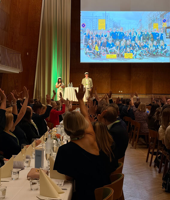 KY Chair of the Board Vilma Paavola and alumni representative Tatu Lehtisyrjä on the stage, the crowd is showing hands.