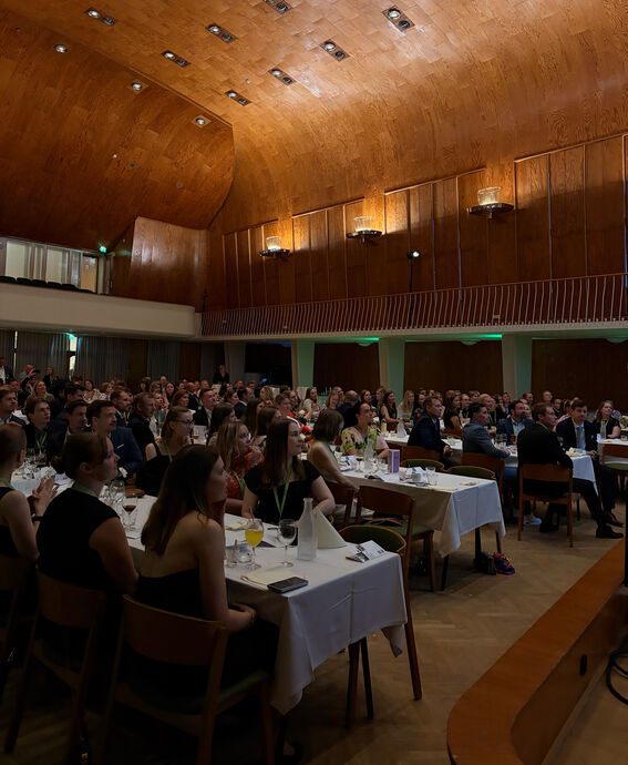 Alumni sitting at the tables and listening to a speech at Aalto University Töölö Assembly Hall