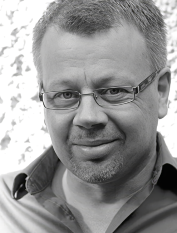 Smiling man with glasses in close-up portrait, short hair, open-collar shirt, light background