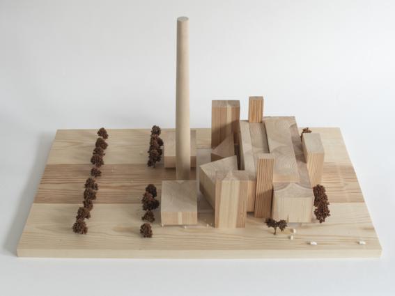 A wooden model of a building with blocks, a tall cylinder, and tiny trees arranged in rows on a light wood base.
