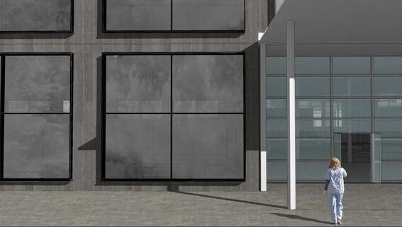 A person walks towards a modern building with large dark windows and glass doors.