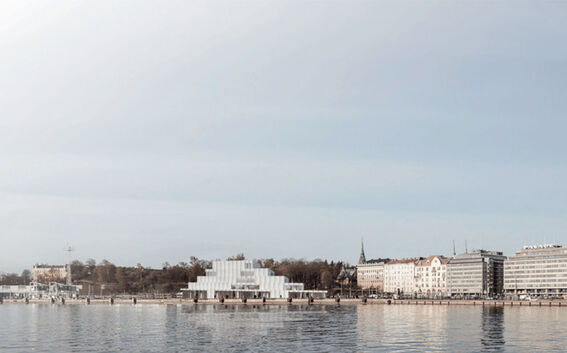 A waterfront view of a city with modern buildings and a stepped glass structure, reflecting in the calm water.
