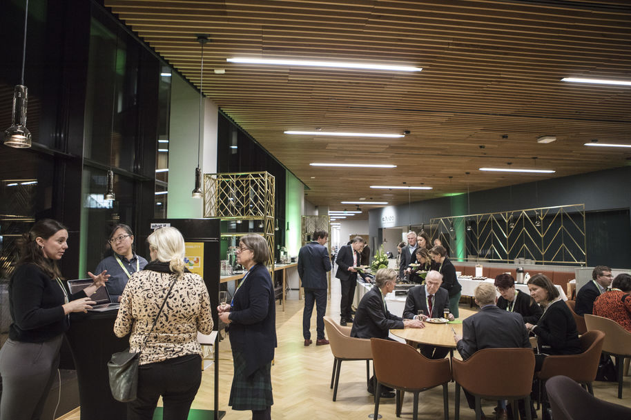 Guests at the School of Business restaurant talking to students at their stand and people sitting at tables and eating.