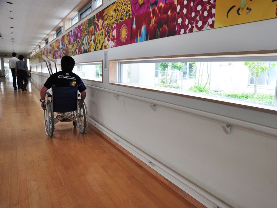 pyörätuolilla liikkuva henkilö näkee ulos käytävän matalalla olevista ikkunoista