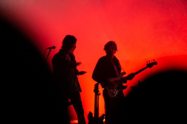 Tame Impala's and band member's black silhouettes against a red backdrop.