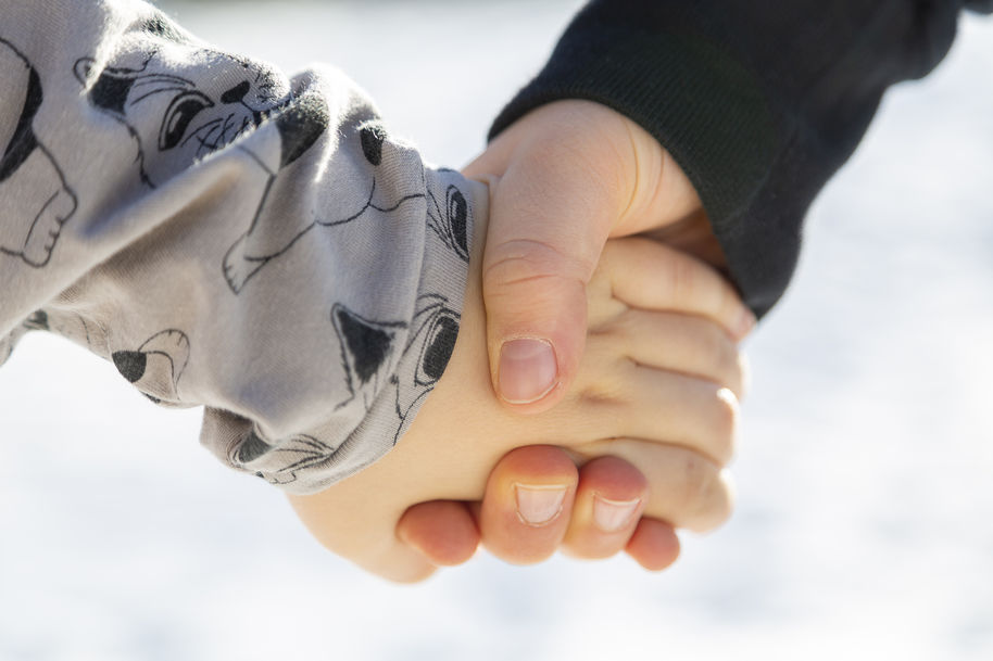 Two children's hands clasped.