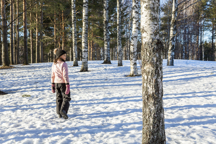 A young child among trees in a snowy park.