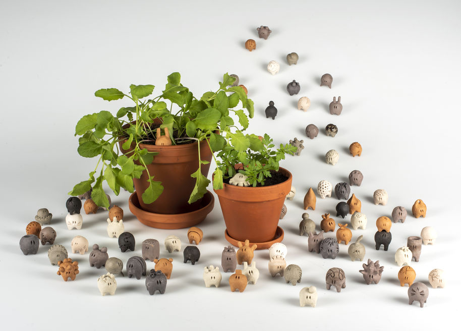 bunch of little creatures next to two plants in pots