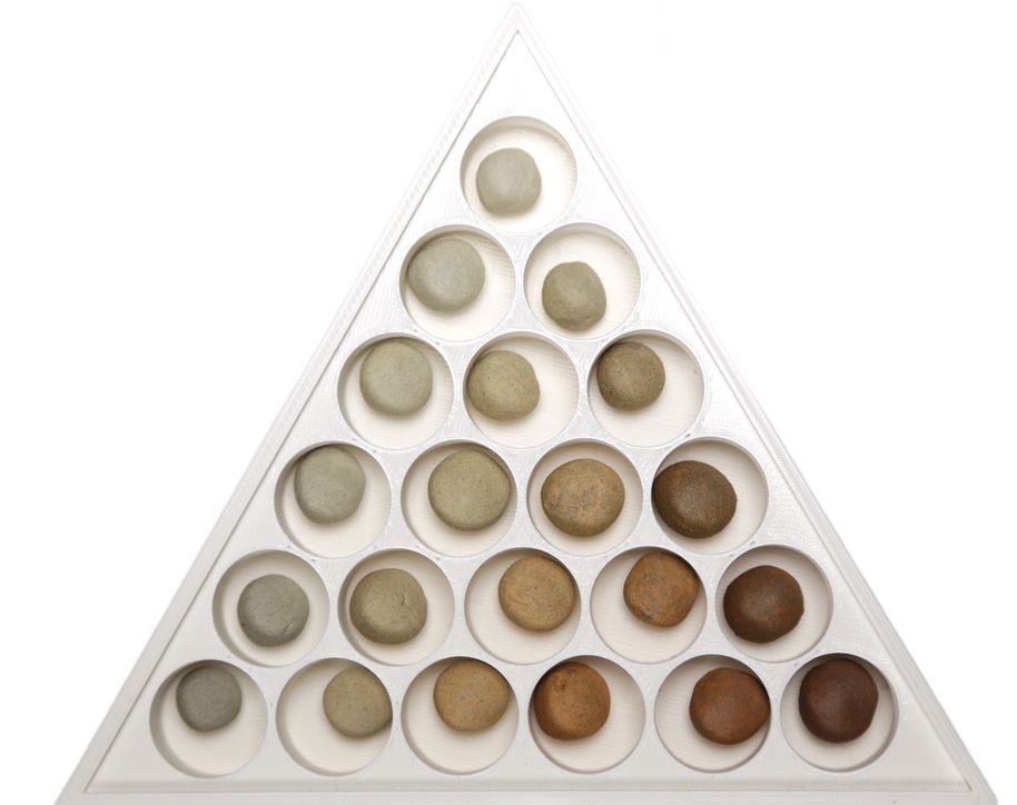 A collection of fired wild clay samples displayed in a triangular container