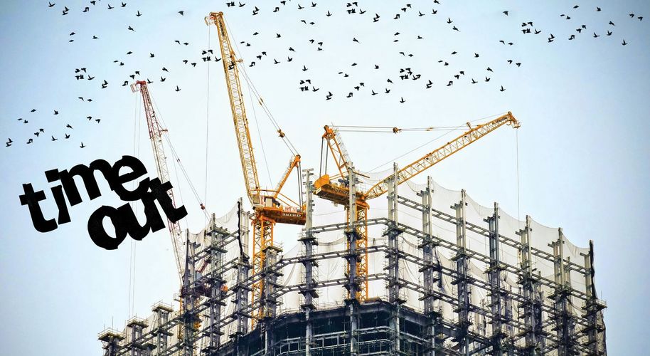 Rakennustyömaan nostureita, joiden yläpuolella lentää lintuja, päällä teksti Time out.