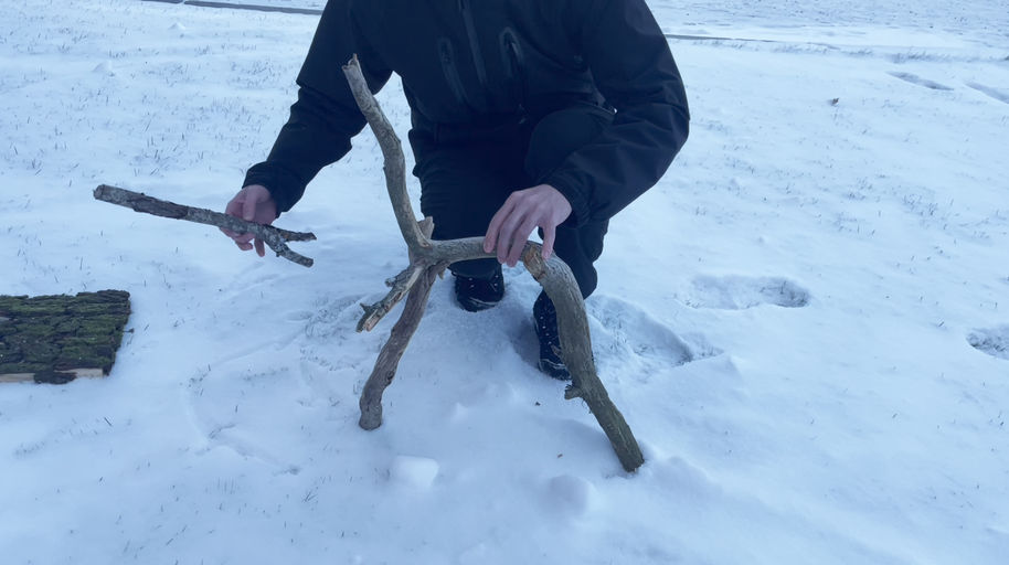 Someone making a wooden sculpture made of pieces found in nature