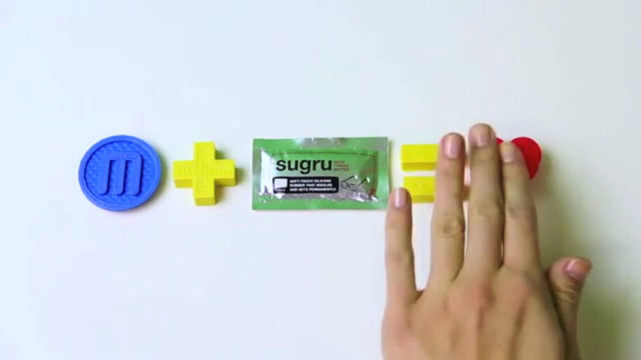 A blue circle, yellow plus sign, Sugru packet, yellow equals sign, red heart, and a hand on a white surface.