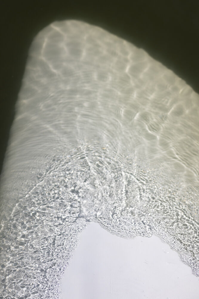 Auringonvalo heijastuu väreilevästä vedestä muodostaen kuvioita veden alla olevalle pinnalle.