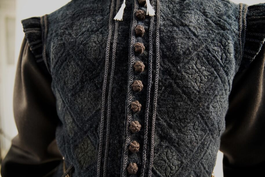 Lähikuva tummansinisestä teksturoidusta liivistä, jossa on yksityiskohtaiset napit ja mustat hihat.