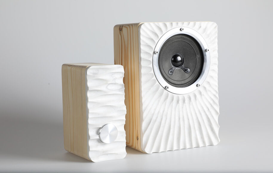 Two wooden speakers with white textured fronts, one with a knob and the other with a circular speaker.