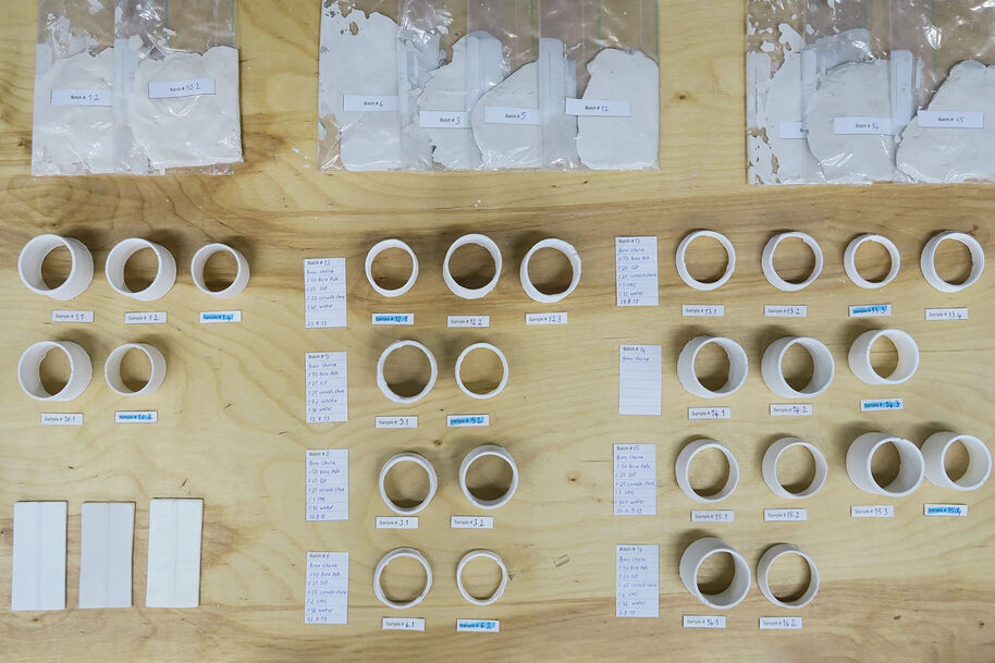 White plastic rings and rectangular pieces arranged on a wooden surface with labels and notes.
