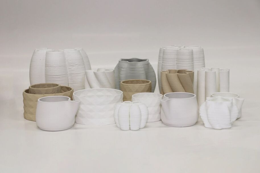 A collection of variously shaped white and beige ceramic pots and vases arranged on a plain background.