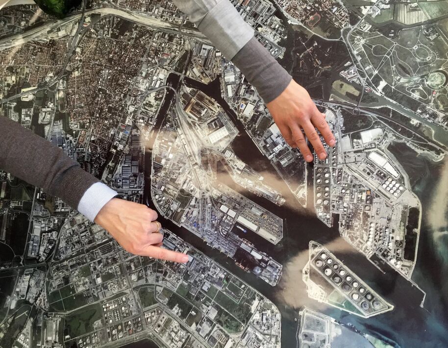 Two hands pointing at different areas on a detailed map of a city with industrial and residential zones.