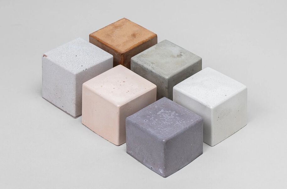 Six concrete cubes in various colours arranged in two rows on a grey surface.