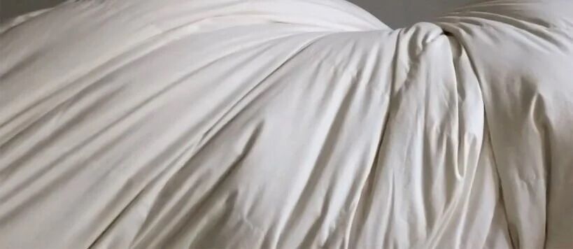 Close-up of white fabric draped and gathered, creating soft folds and wrinkles.