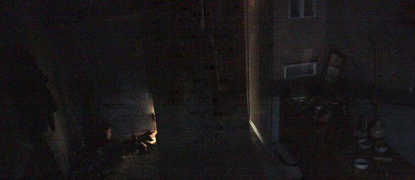 A dimly lit room with a table, some objects, and a small light source near the floor.