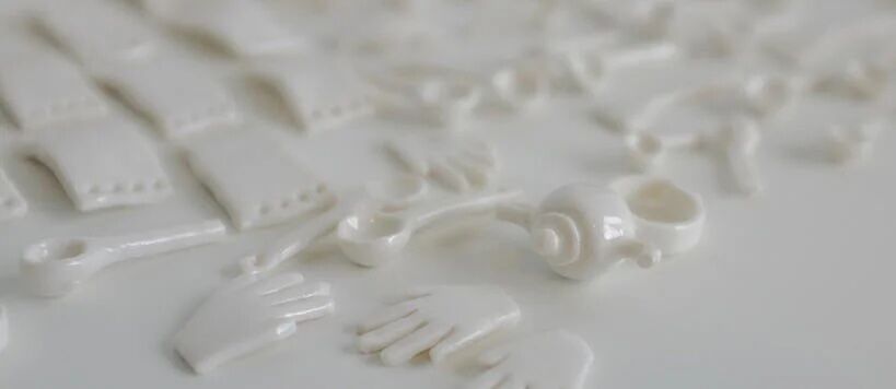 White ceramic pieces including hands, arms, and other shapes arranged on a light surface.