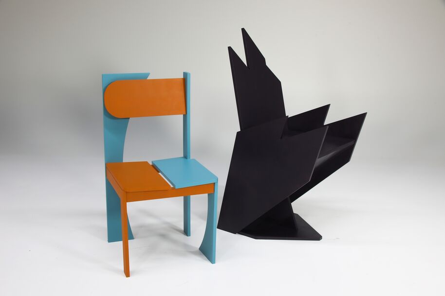 A modern chair with orange and blue geometric shapes next to a black abstract chair on a white background.