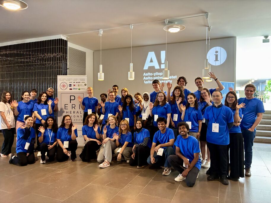 Large group of smiling students volunteers in blue T-shirts posing and waving indoors at WPSC Congress