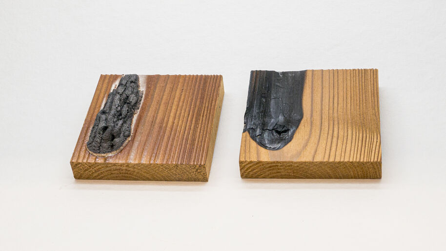 Two square wood blocks with rough black charred patches set in their smooth brown grain.