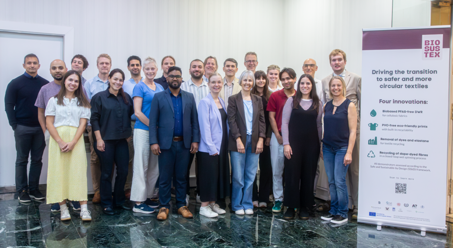 Diverse project team posing indoors beside a BIOSUSTEX textile innovation banner