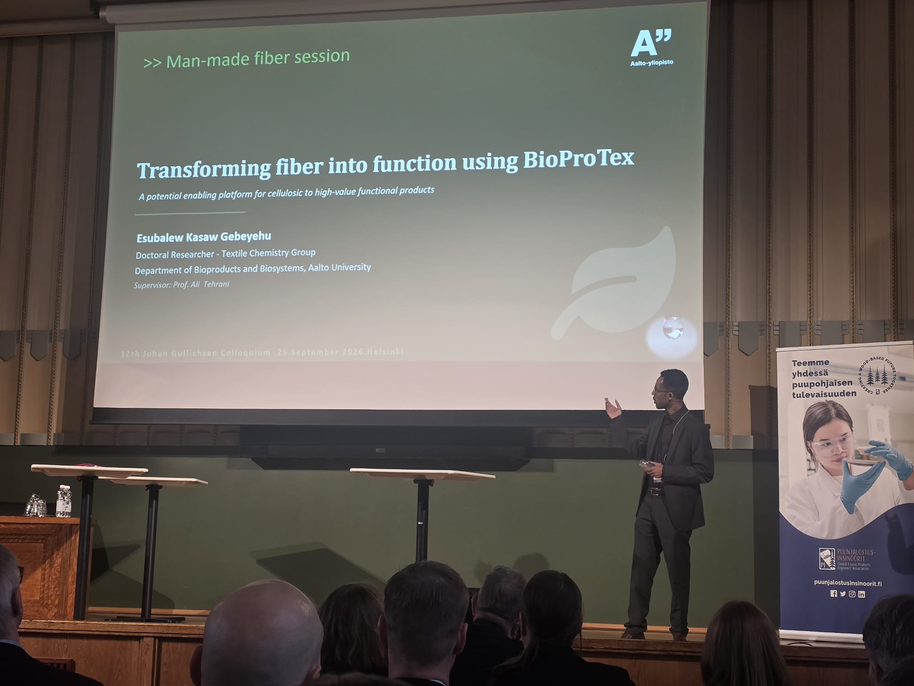 Speaker presenting BioProTex fibre research on a large screen in a lecture hall with seated audience
