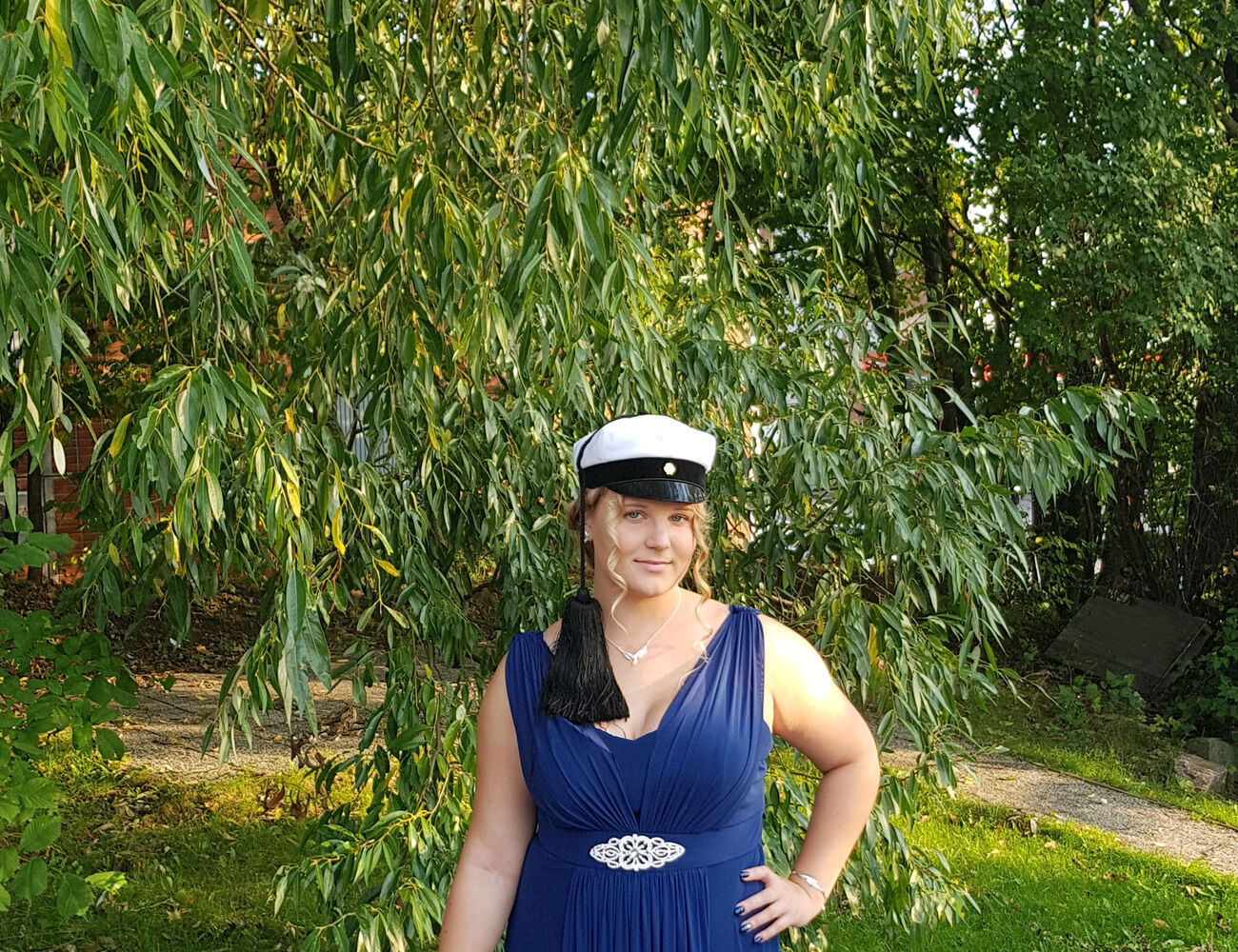 Jonna in a ballgown in the park wearing a Teekkari cap