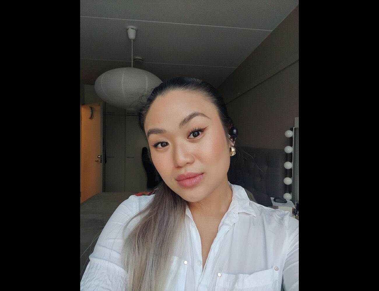 Mimi Tran kuvattuna asunnossa, itseottama kuva. Taustalla kattolamppu ja vasemmalla avoin ovi.