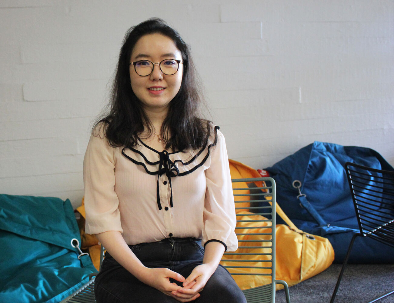 Meishan Lin sitting in a chair at the School of Chemical Engineering lobby. Colourful bean bag chairs in the background.