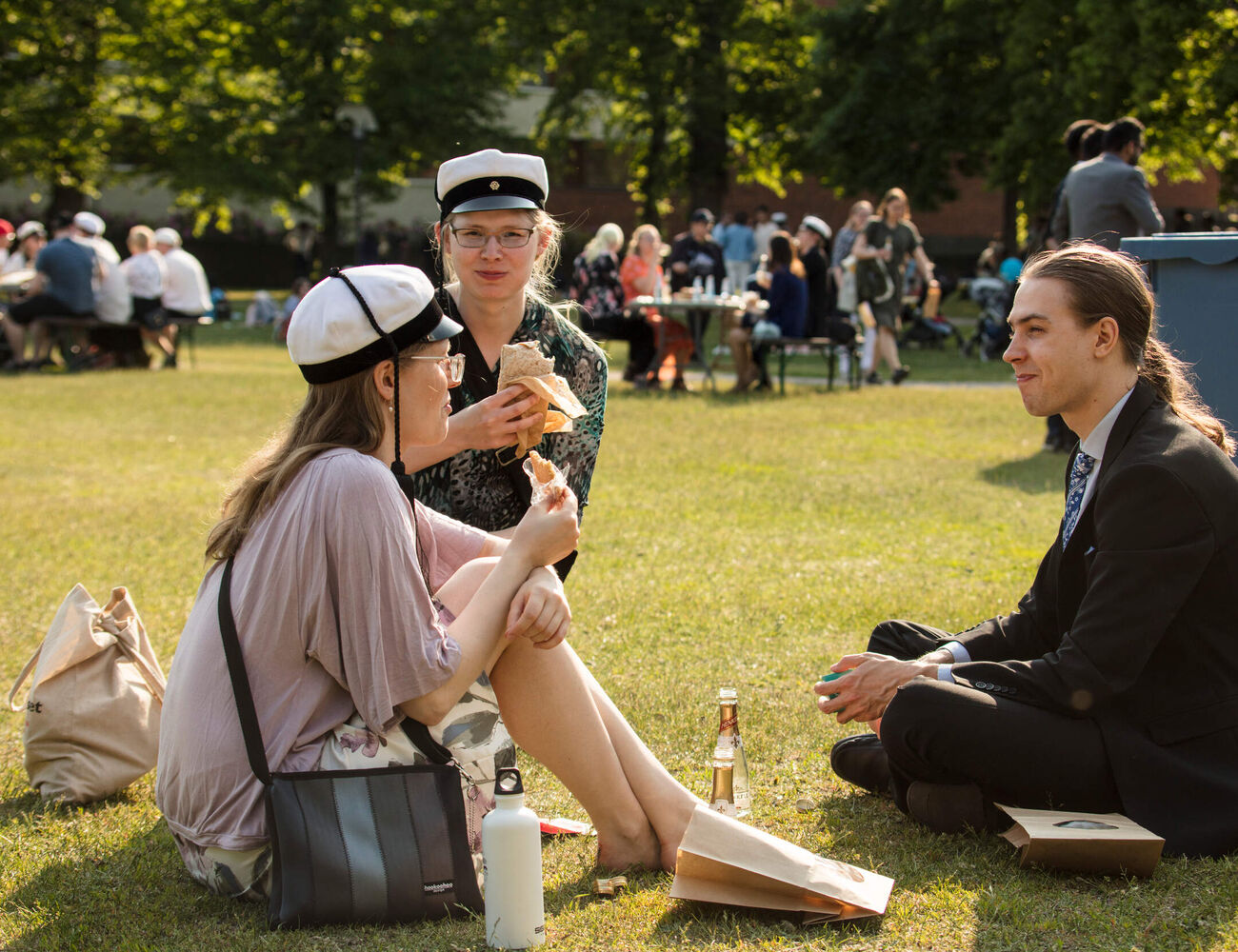 Three graduates sitting and having a picnic at the park